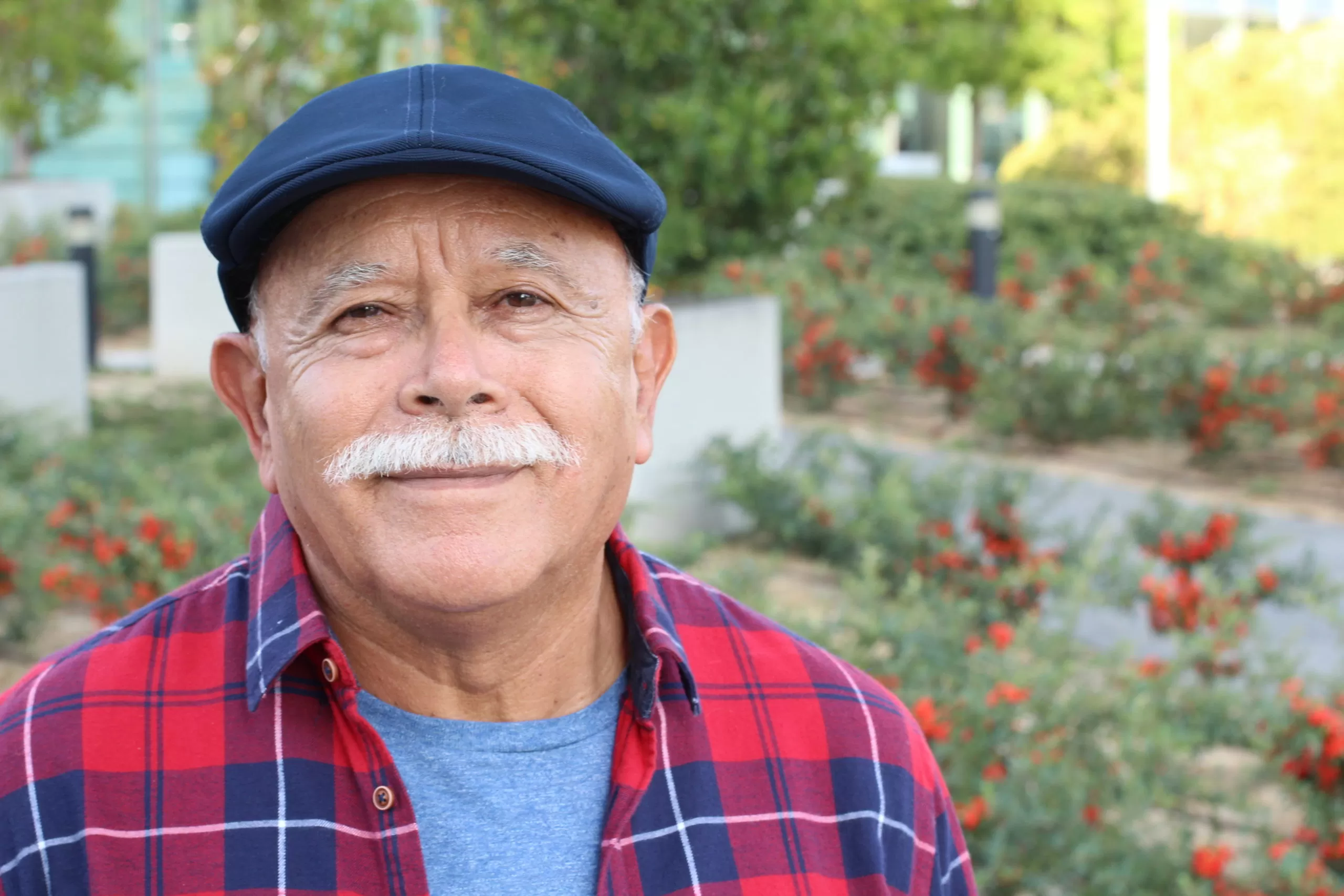 Smiling senior Hispanic man in an outdoor setting, captured in a natural light headshot.