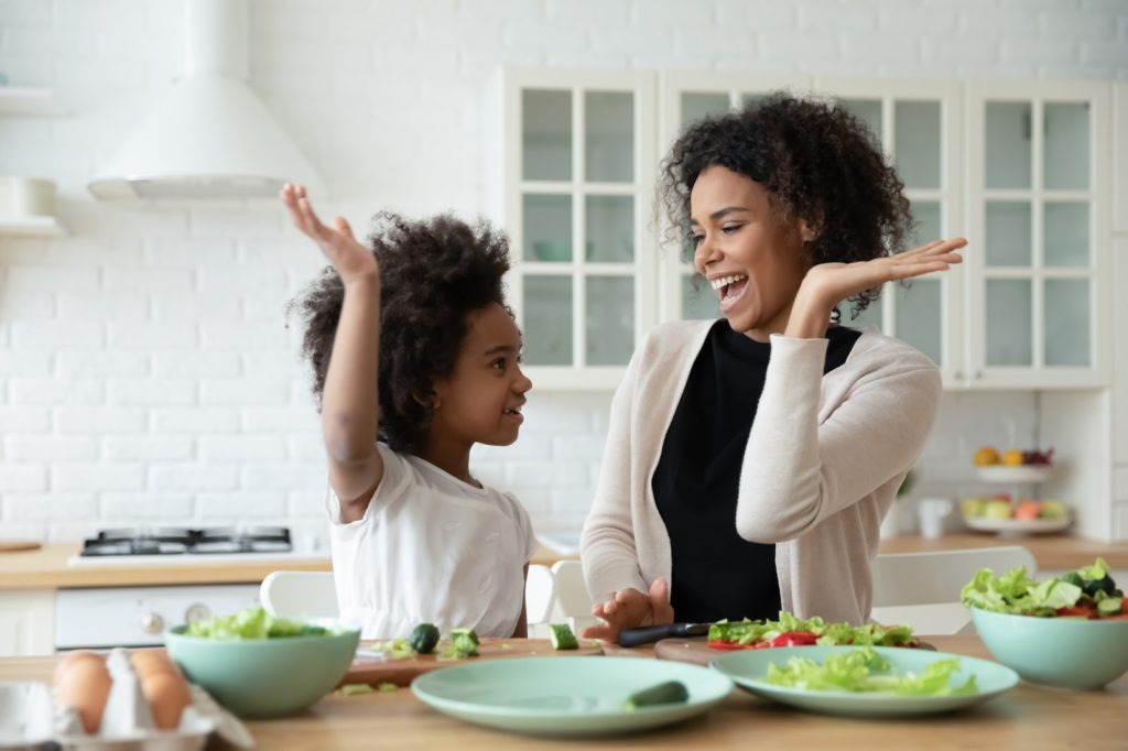 A mom and her daughter high-fiving after eating a healthy salad