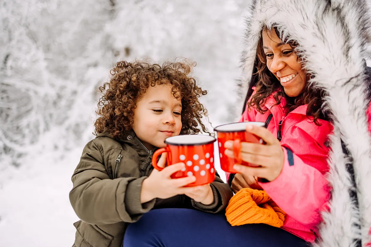 Mother and daughter drinking warm tea during winter time